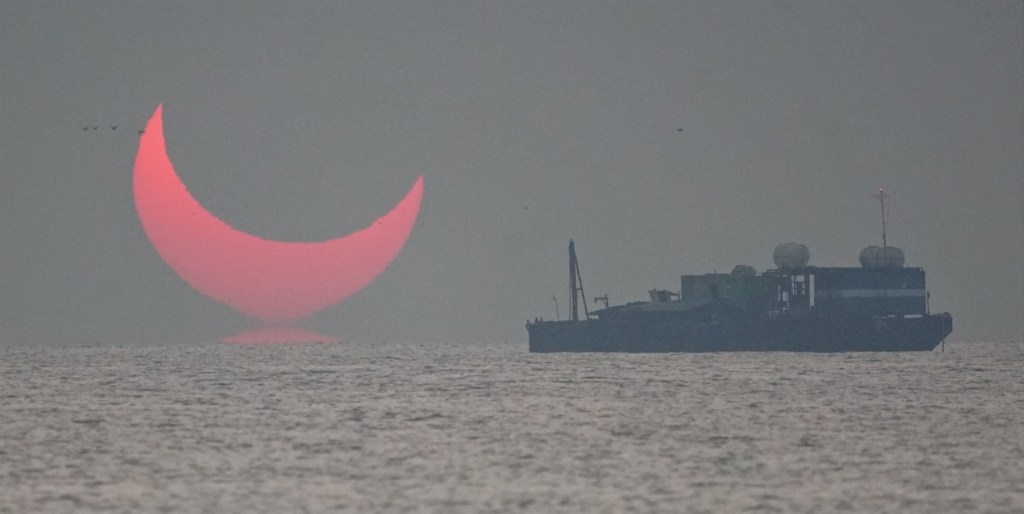 The sun, partially blocked by the moon, rises above the sea in Al Wakrah, Qatar, Dec. 26, 2019. Facebook and Twitter users were quick to draw comparisons between the reddened partial eclipse to "devil horns."