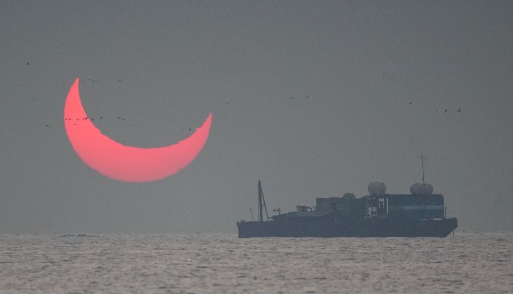 The sun, partially blocked by the moon, rises above the sea in Al Wakrah, Qatar, Dec. 26, 2019. Facebook and Twitter users were quick to draw comparisons between the reddened partial eclipse to "devil horns."